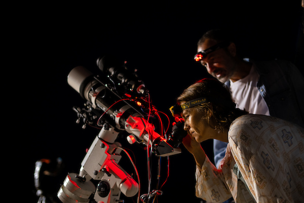 Mujer observando el cielo en la noche con material profesional y acompañada de un hombre